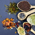 Xícara de chá natural acompanhada de ervas, representando uma alimentação saudável e hábitos que podem auxiliar no emagrecimento.