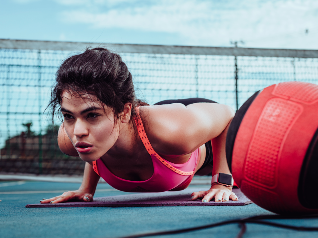 Exercícios para Iniciantes: Como Começar a Treinar com Segurança e Obter Resultados Reais Mulher realizando exercício de flexão no chão com postura correta, demonstrando um treino para iniciantes focado no fortalecimento muscular, melhora do condicionamento físico e prática segura de exercícios.