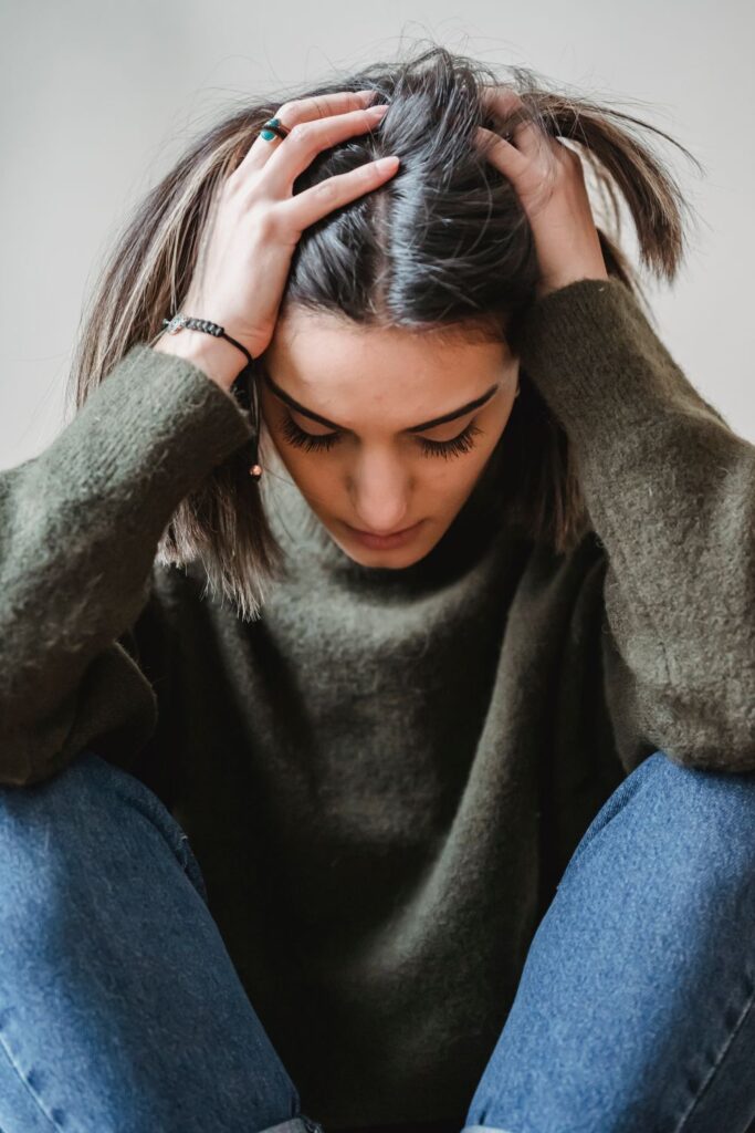 Ansiedade e Depressão: Os Sintomas que Você Nunca Deve Ignorar Mulher sentada em um ambiente tranquilo, com expressão de ansiedade e preocupação, enquanto respira profundamente em busca de aliviar a tensão. A prática regular de exercícios físicos, como caminhadas, corrida, yoga ou alongamentos, pode ajudar a reduzir os sintomas de ansiedade, melhorar o humor e promover mais equilíbrio para a saúde mental.