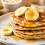 Panqueca de banana saudável servida em um prato com fatias de banana e mel, ideal para café da manhã ou lanche nutritivo.